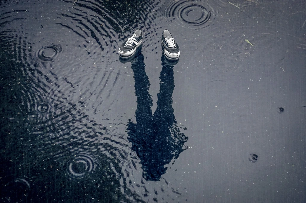 Empty shoes above a person's reflection